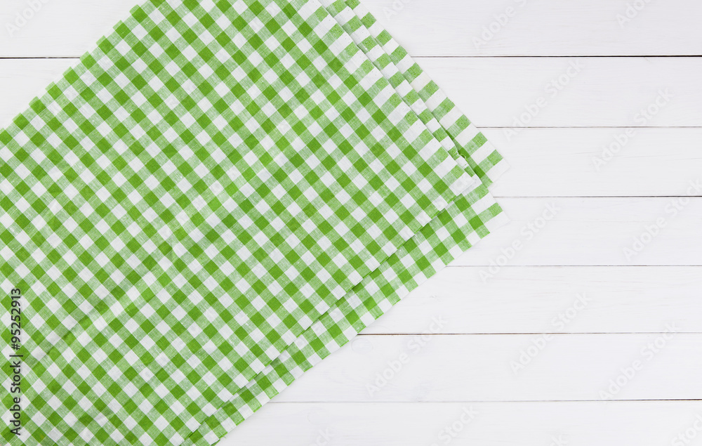 白色木制厨房桌子上的绿色毛巾。从上面看，有复制空间