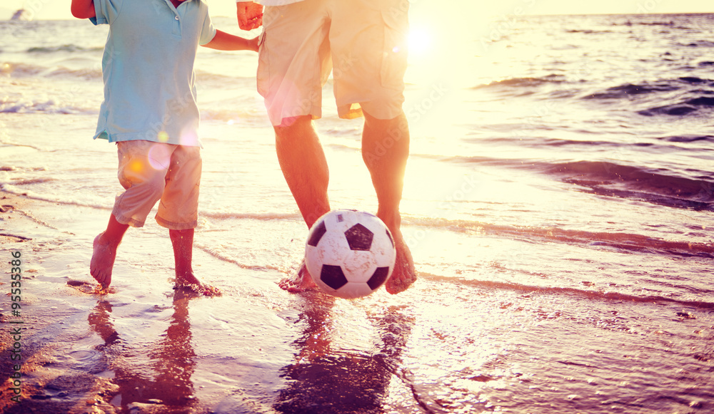 父子在海滩踢足球夏季概念赛