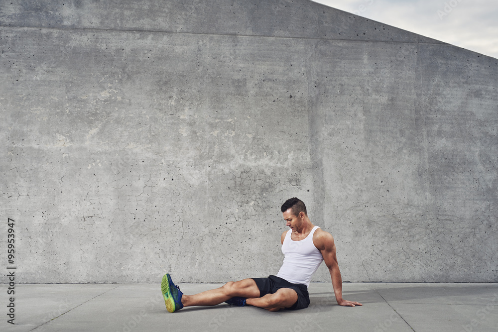 健身运动员男子放松和伸展肌肉和腿部
