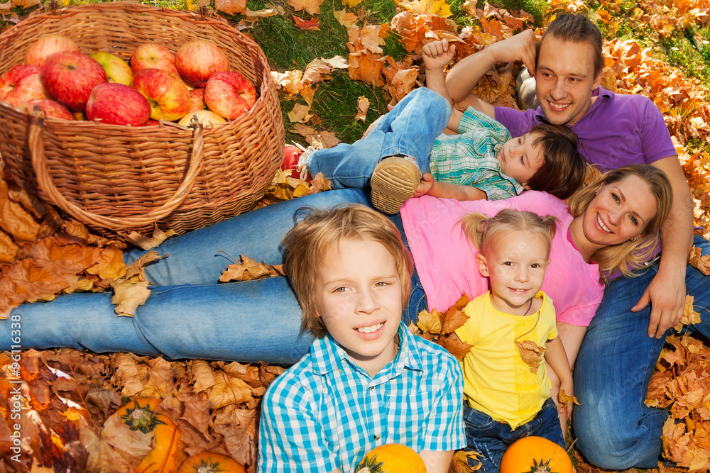 Family laying on grass with orange autumn leaves