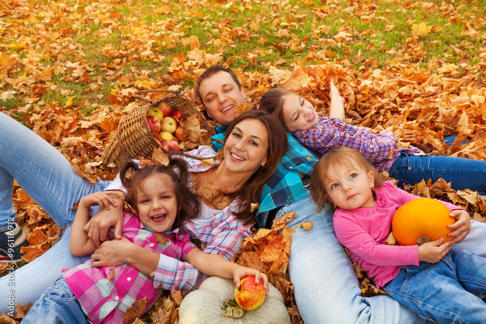 Family with three girls lay in the maple leaves