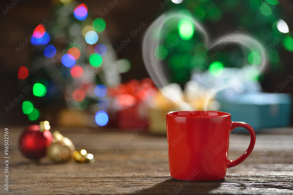 一杯带有心形烟雾的咖啡，周围环绕着圣诞灯上的圣诞装饰