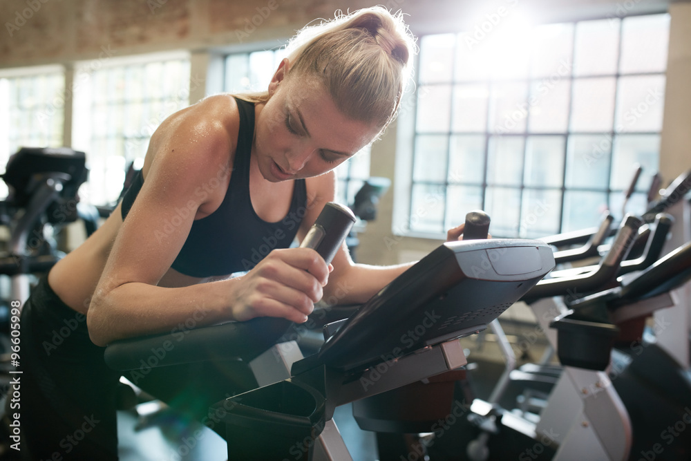 Fit young female exercising on gym bike
