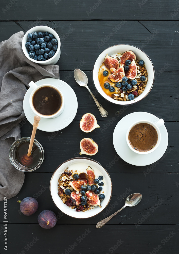 Healthy breakfast set. Bowls of oat granola with yogurt, fresh blueberries and figs, coffee, honey, 