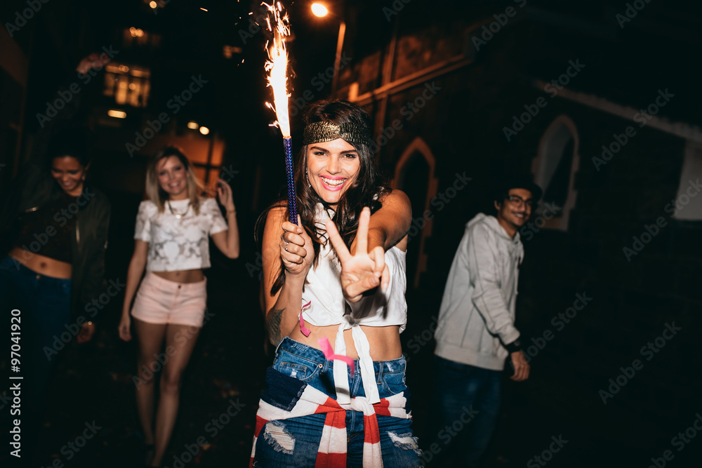 兴高采烈的年轻女子拿着焰火在派对上享受