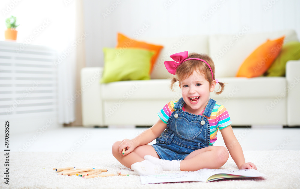 快乐的小女孩躺在地板上用彩色铅笔画画