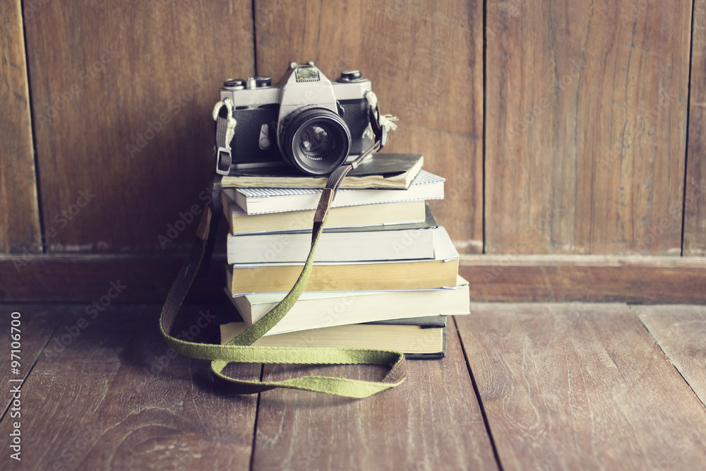 木地板上一堆书上的老式相机