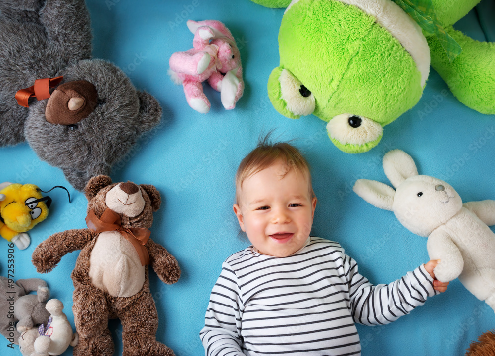 快乐的一岁男孩和许多毛绒玩具一起躺着