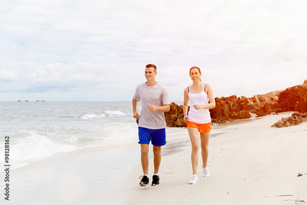 跑步者。海滩上跑步的年轻夫妇