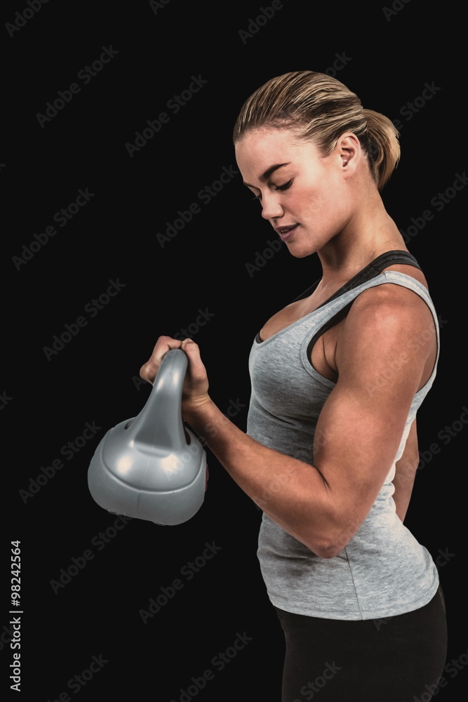 严肃的肌肉女性举起壶铃的合成图像