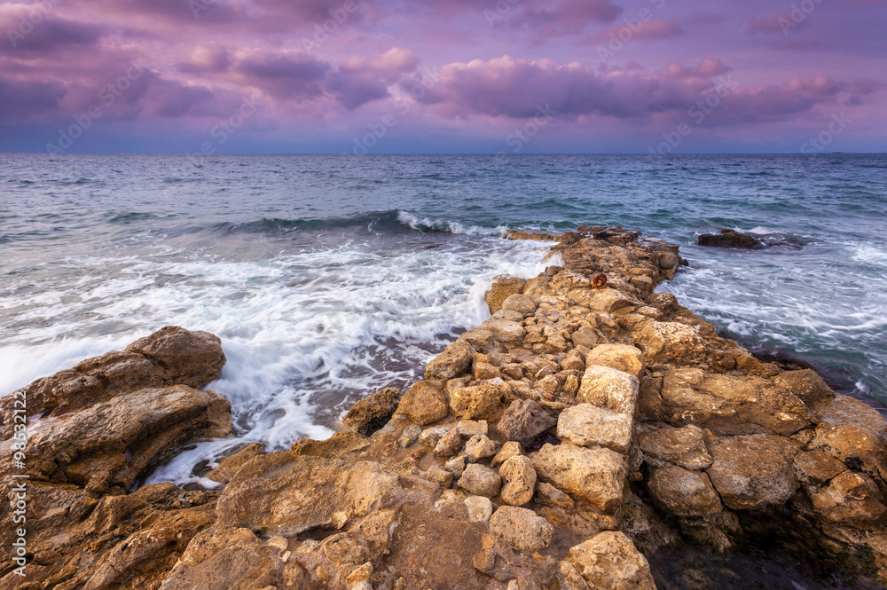 日落时海滩上的海浪和岩石