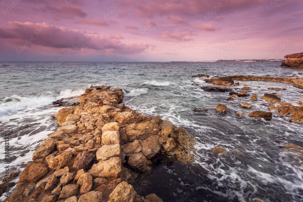 日落时海滩上的海浪和岩石