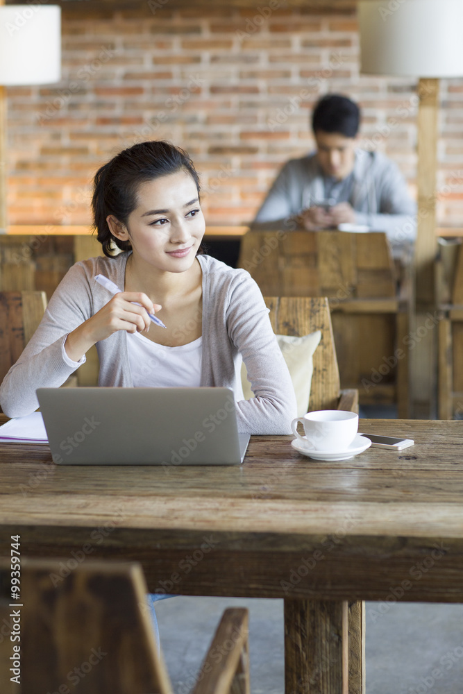 年轻女子在咖啡馆使用笔记本电脑