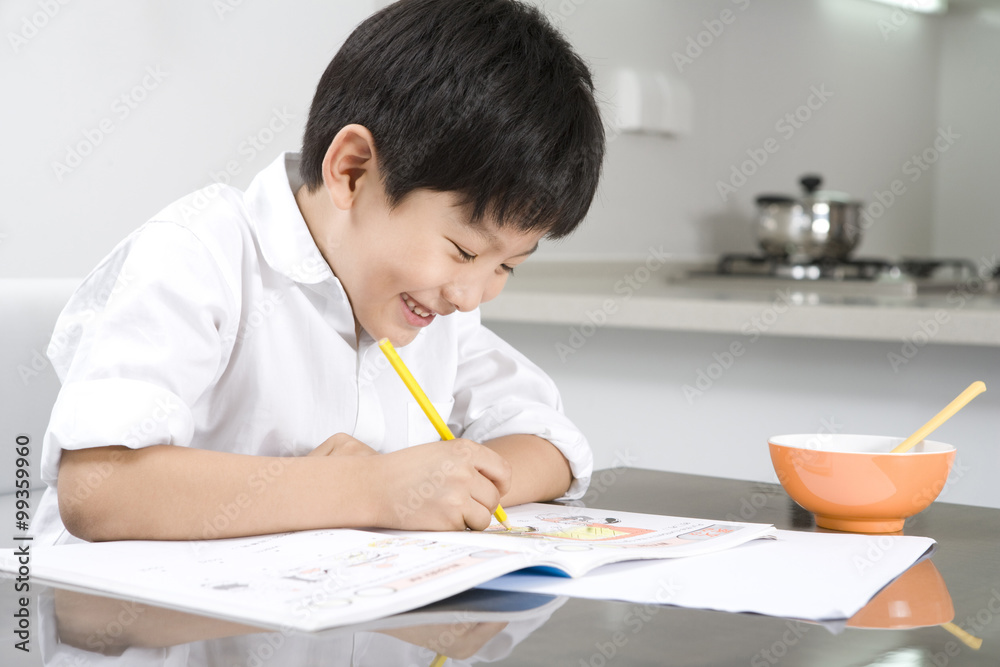 Young boy doing homework in kitchen