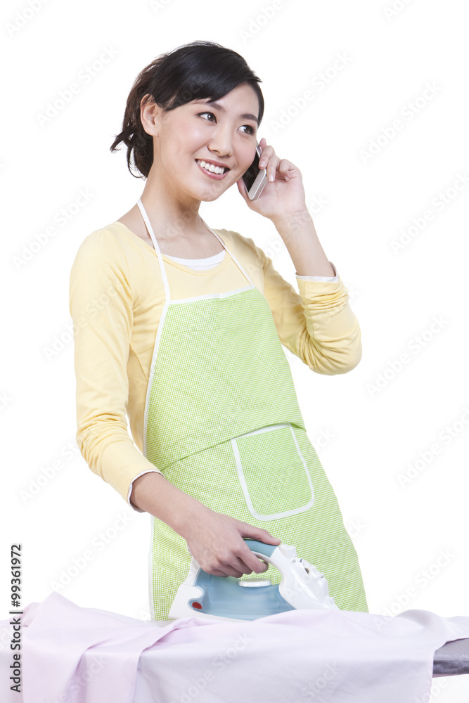 Housewife talking on the phone while doing ironing