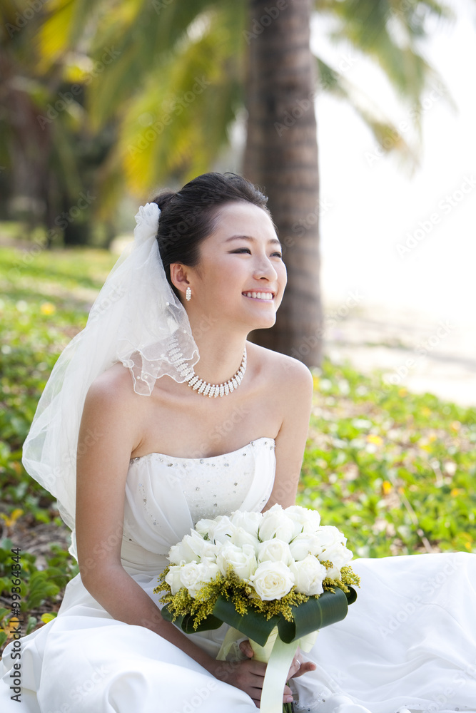 Happy bride sitting on the beach