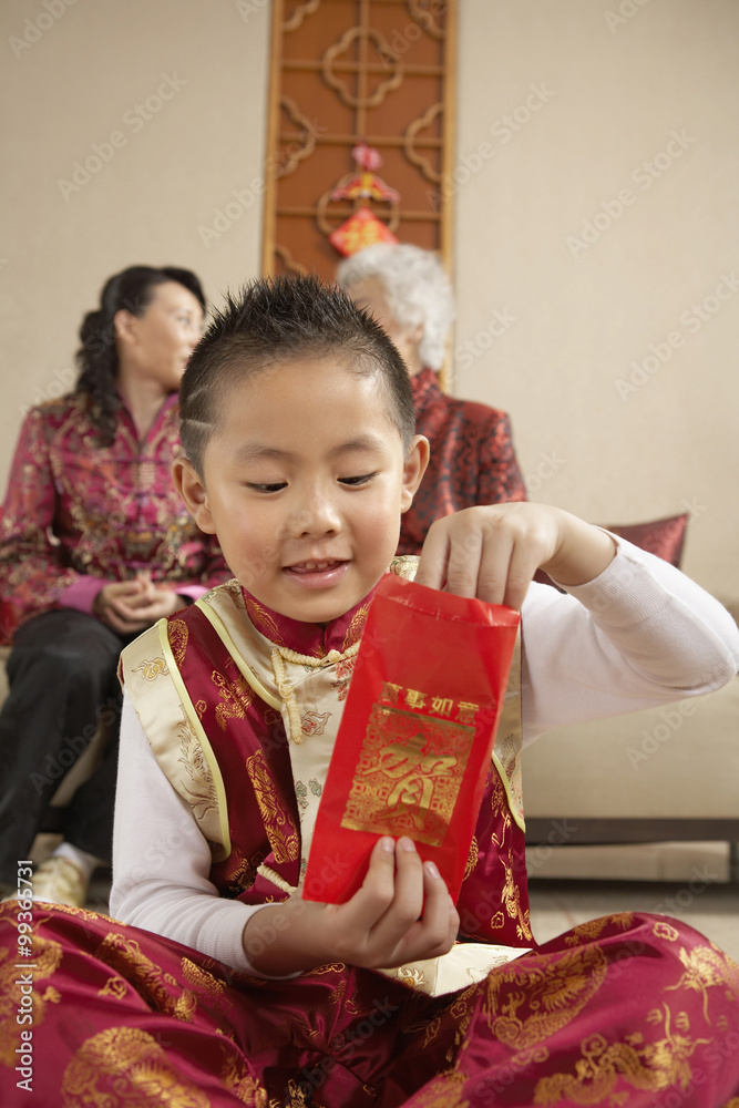 穿着传统服装的年轻男孩打开礼物