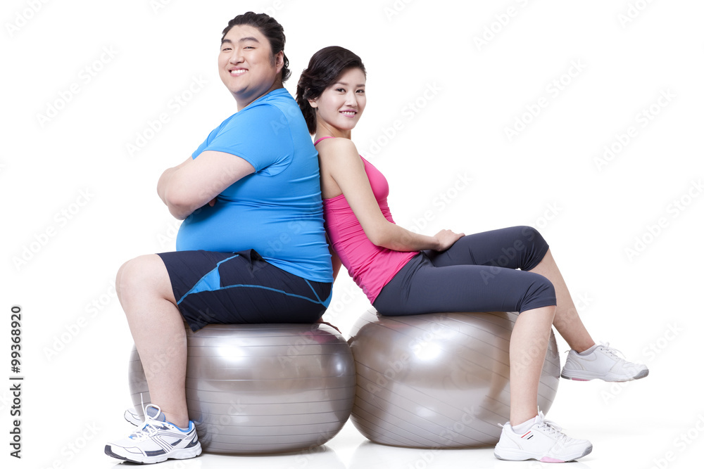 身材魁梧的男子和女友背靠背坐在健身球上