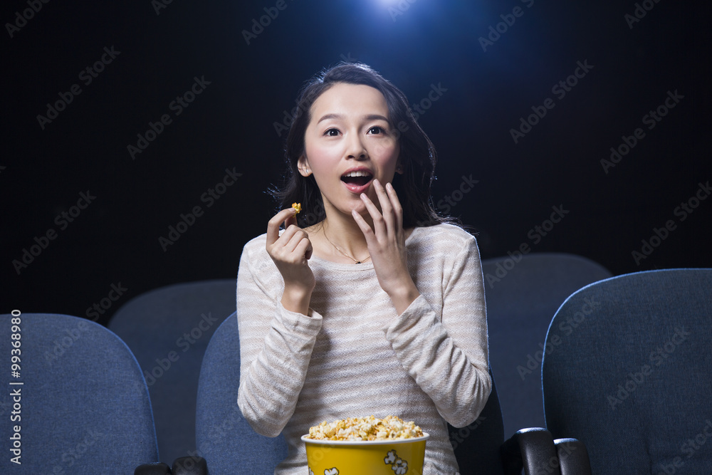 年轻女人手里拿着爆米花在电影院看电影