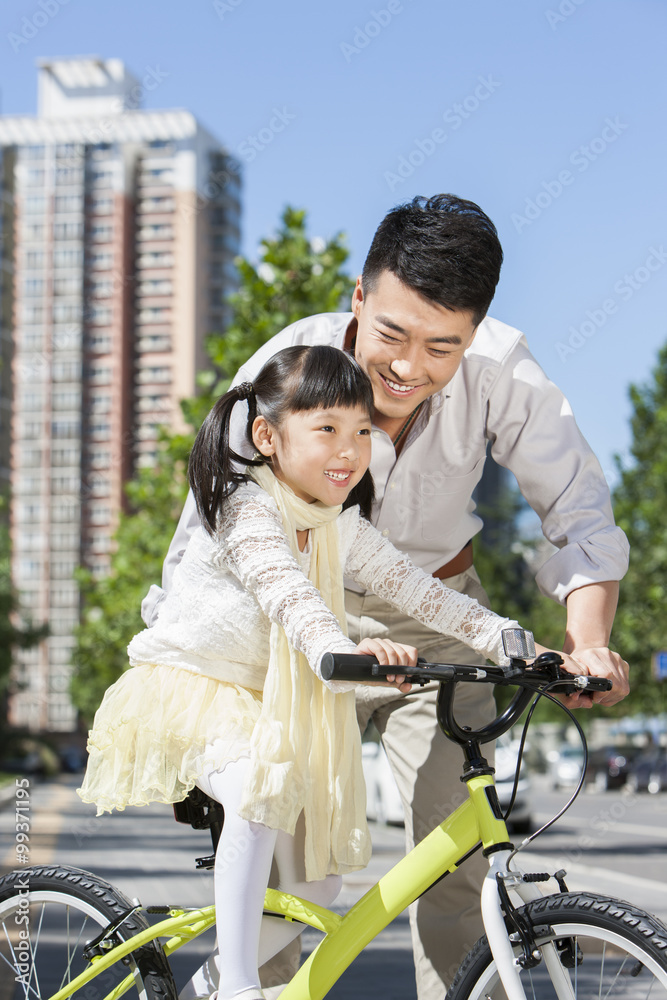 好心的年轻父亲在街上教儿子骑自行车