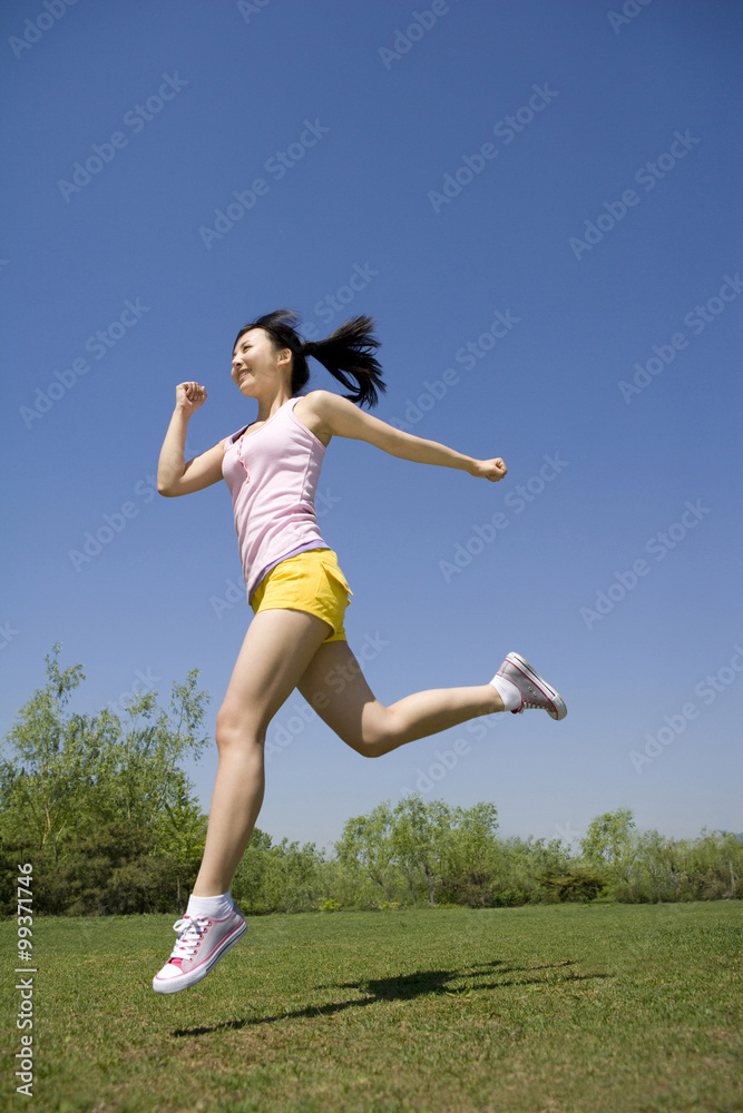 年轻女子在公园跳到空中