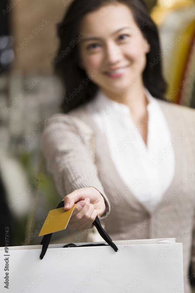 年轻女子在服装店出示信用卡