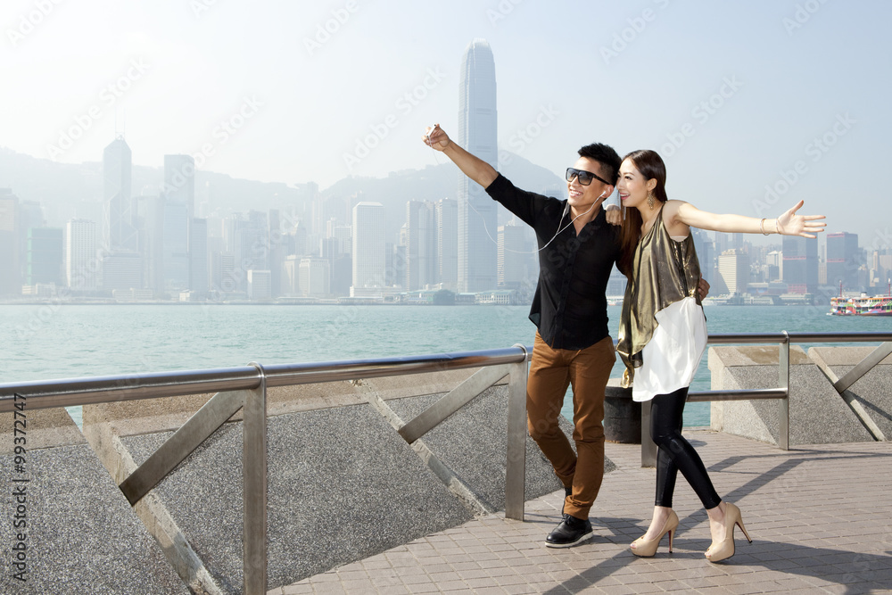 香港维多利亚港，时尚年轻夫妇用智能手机自拍
