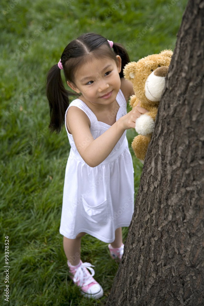 年轻女孩帮助她的泰迪熊爬树