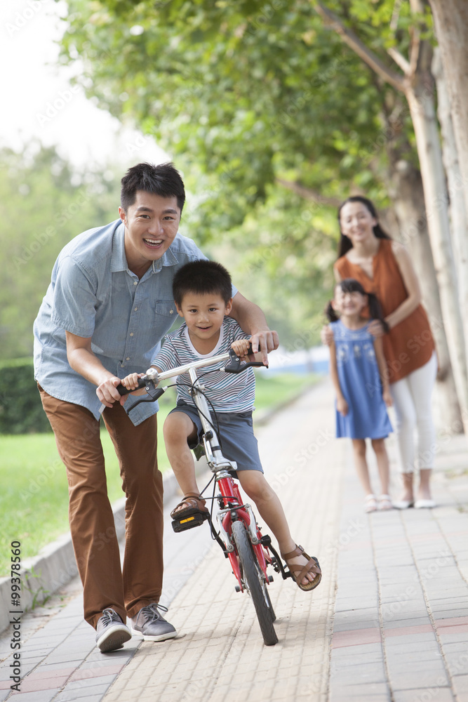 年轻的父亲教儿子骑自行车