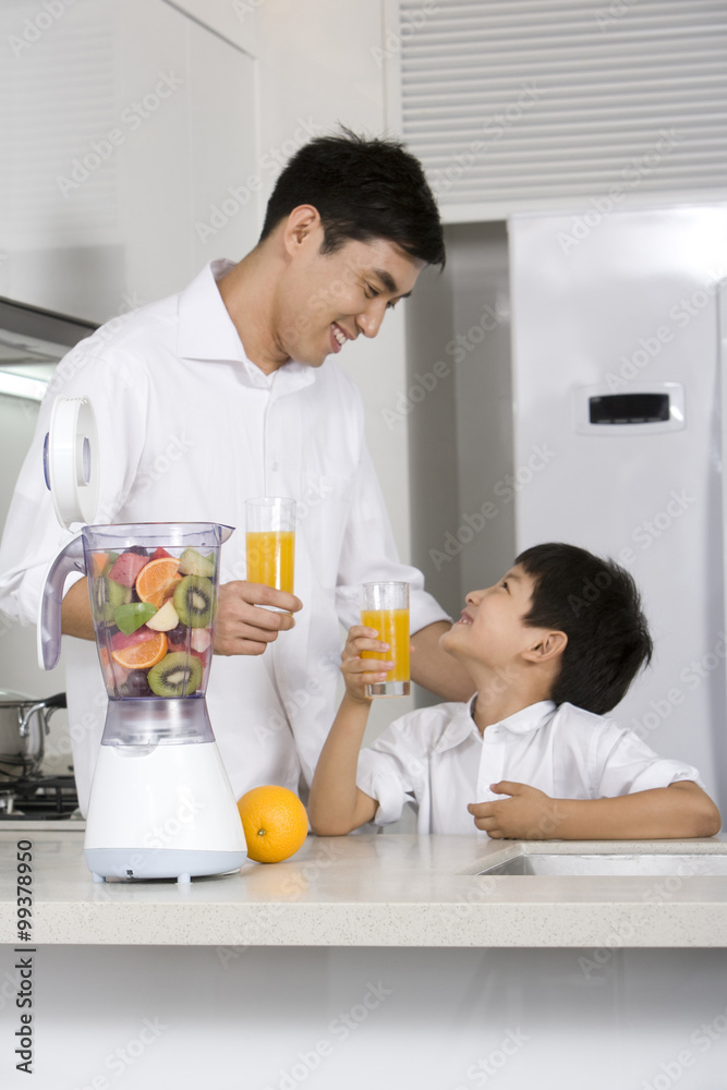 Father and son making fresh fruit juice in kitchen