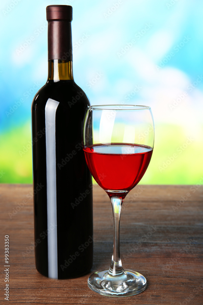 在模糊的自然背景下，装在玻璃杯和瓶子里的葡萄酒