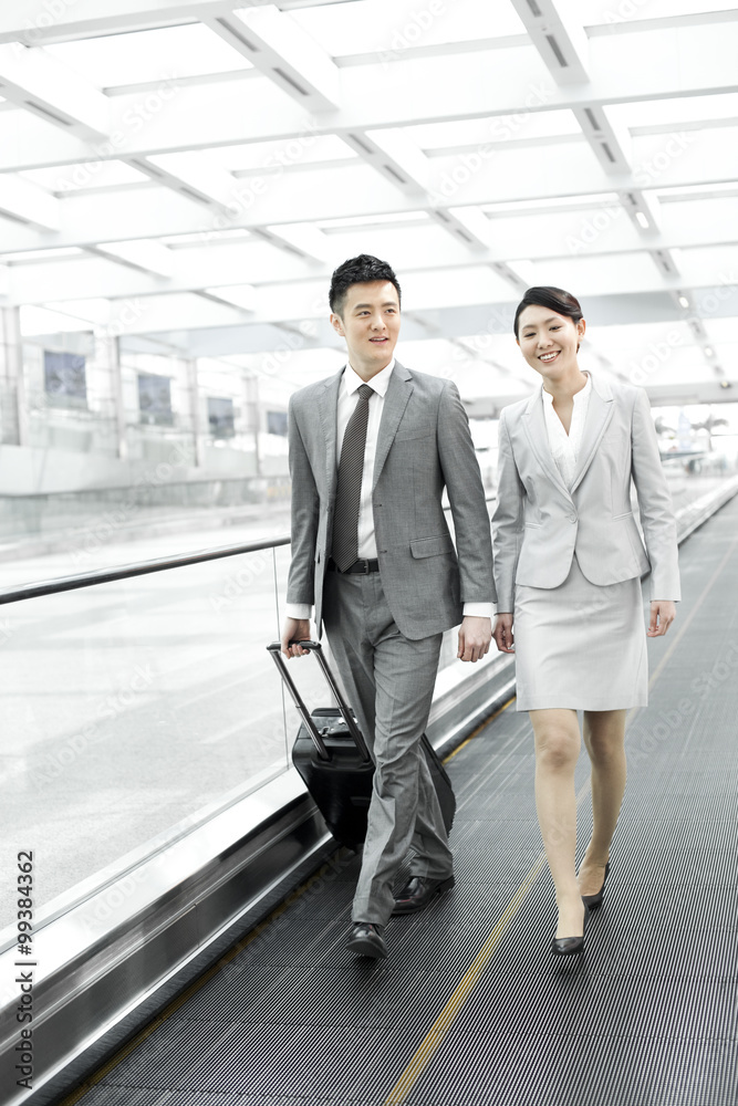 Business colleagues with luggage on airport escalator