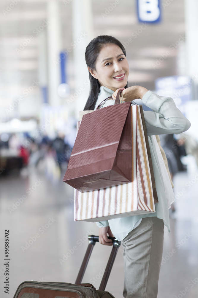 拿着购物袋在机场等候的成熟女人