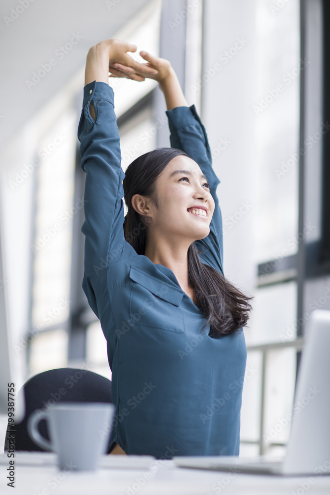 Young businesswoman stretching in office