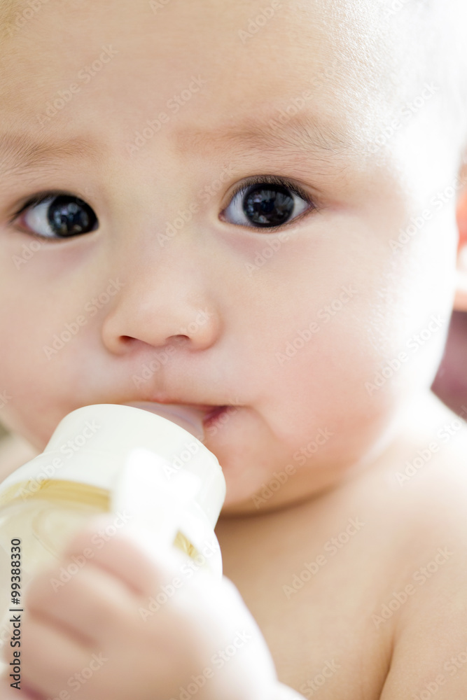Cute baby boy drinking water from feeding bottle