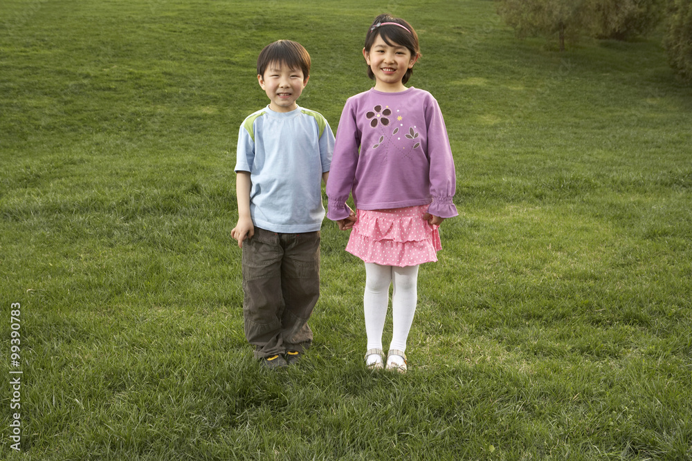 站在公园里牵手微笑的年轻男孩和女孩