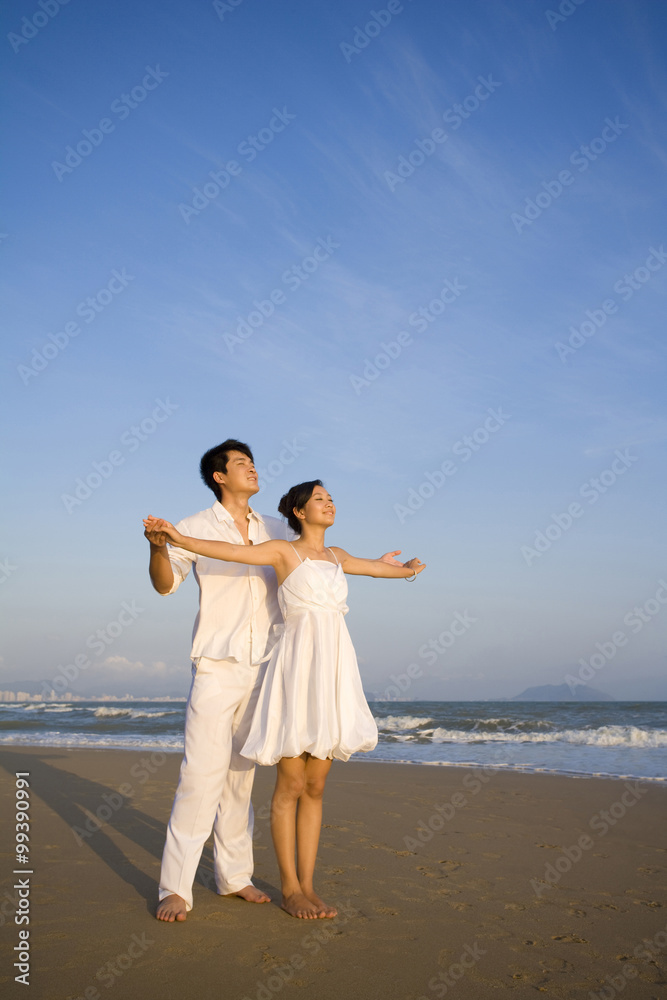 海滩上穿着白色衣服的年轻情侣