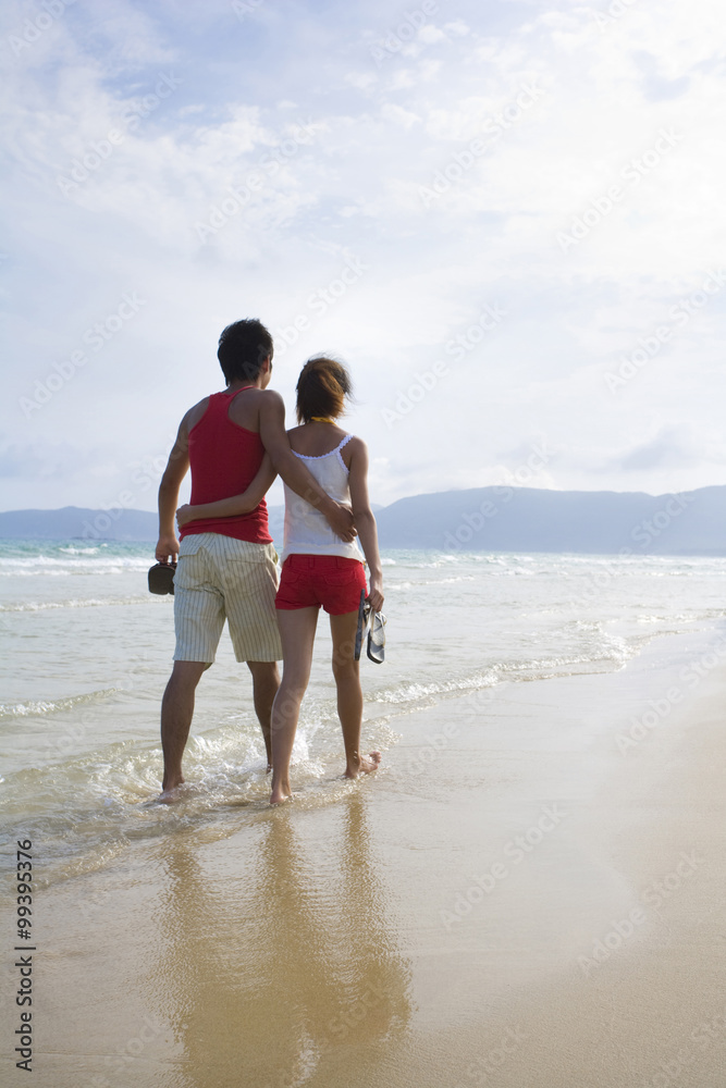 年轻情侣在海滩上浪漫漫步