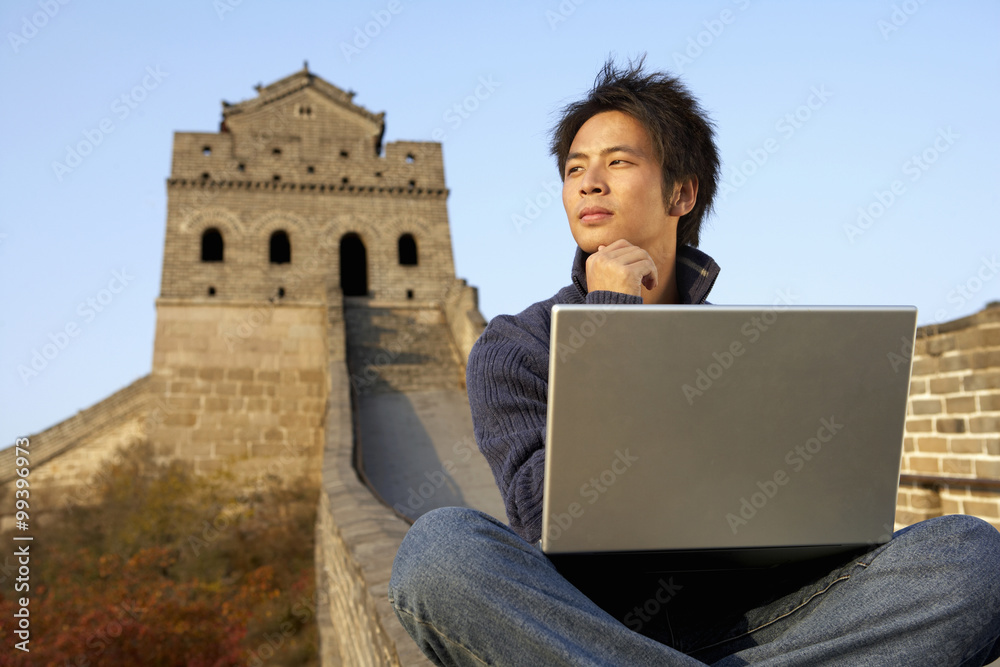 年轻人在中国长城上使用笔记本电脑