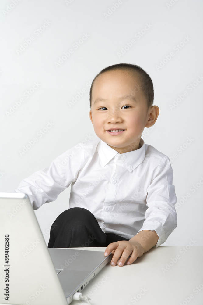坐在笔记本电脑旁的年轻男孩