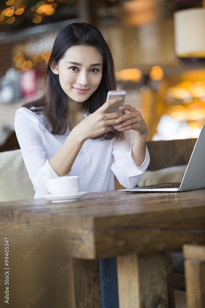 Portrait of woman using smartphone while sitting in cafÈ