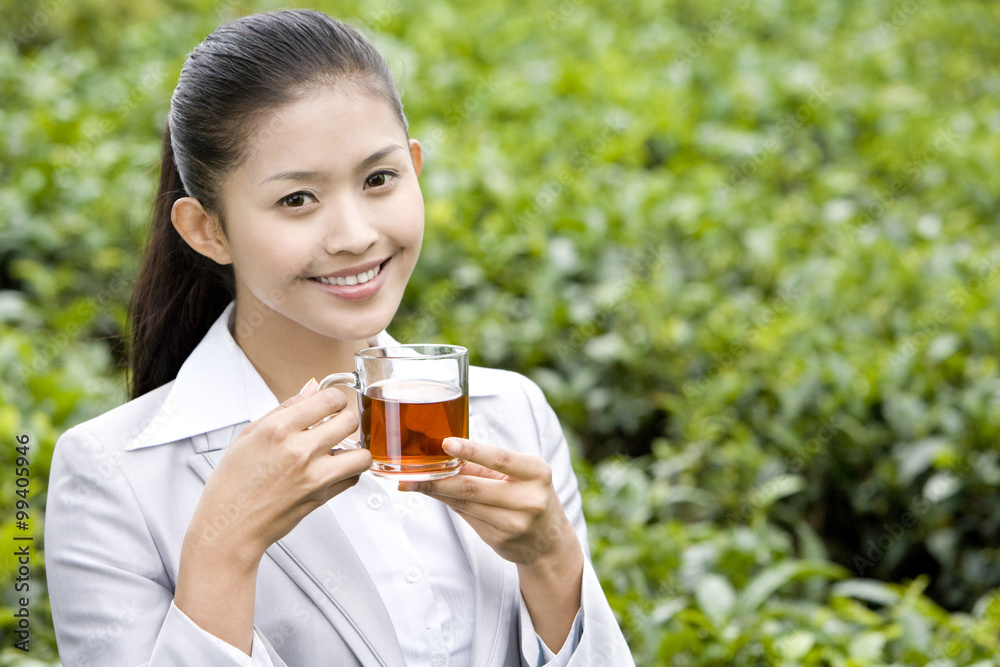 Young Businesswoman in Tea Field with Freshly Brewed Tea