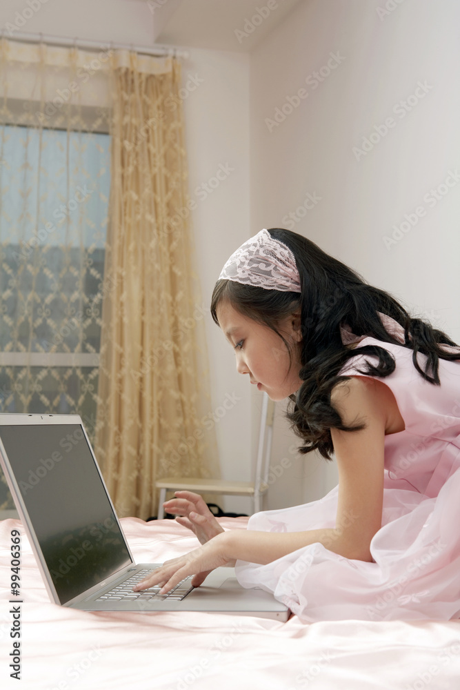 女孩坐在床上使用笔记本电脑