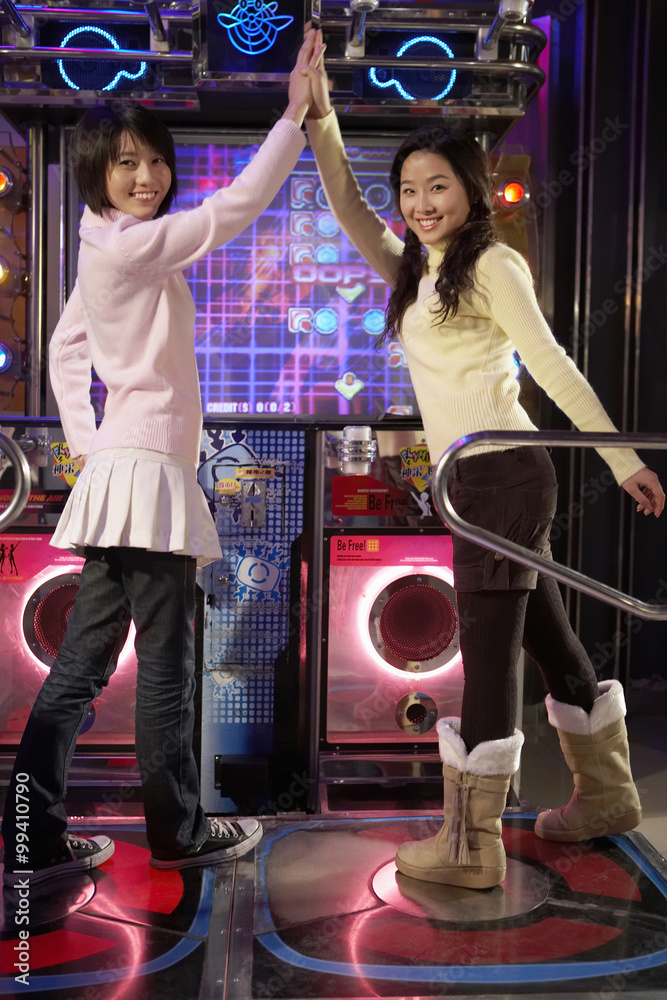 Teenage Girls On Dancing Game At Arcade