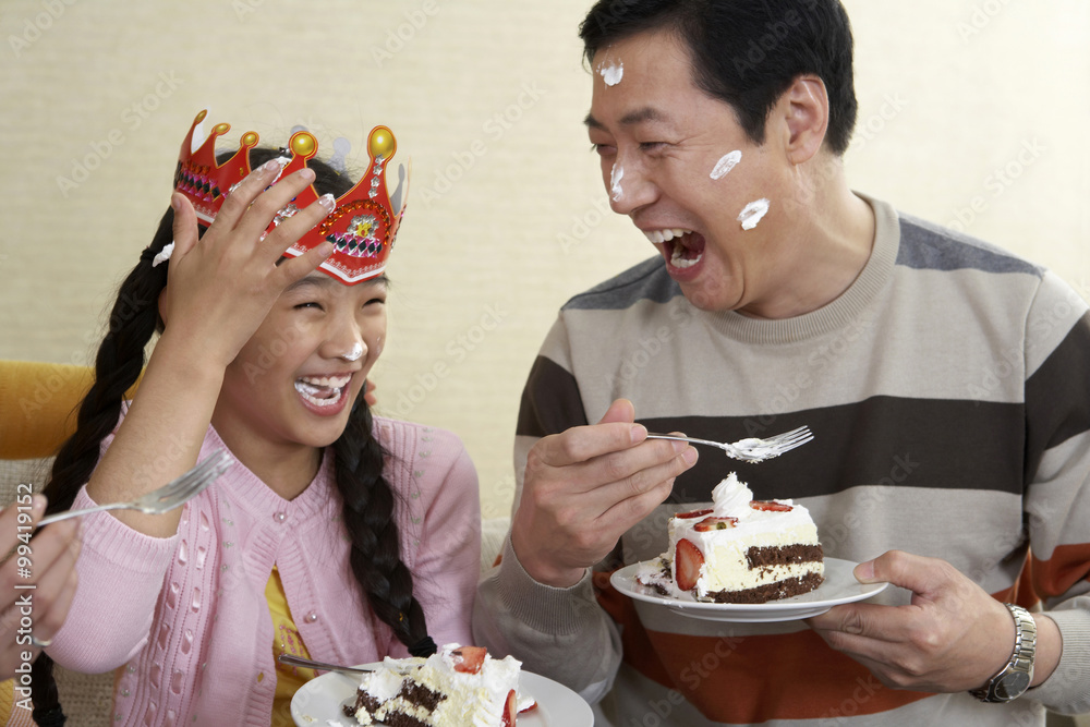 Father And Daughter Eating Birthday Cake With Cake On Their Faces