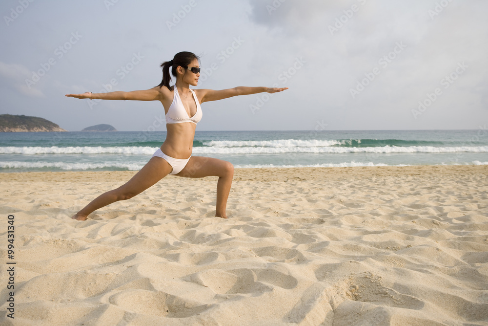 年轻女子在海滩上做瑜伽