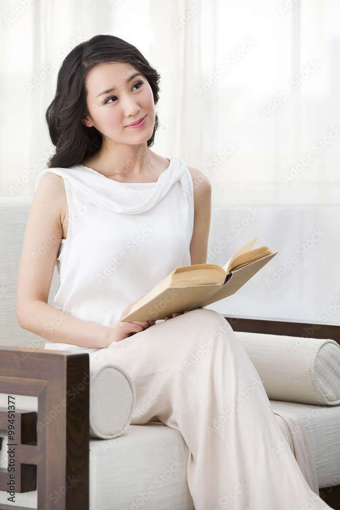 Young woman sitting in armchair and reading