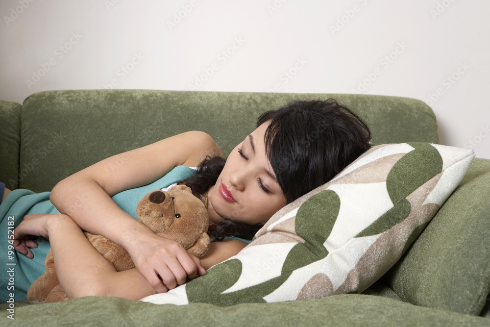 抱着泰迪熊睡在沙发上的女人
