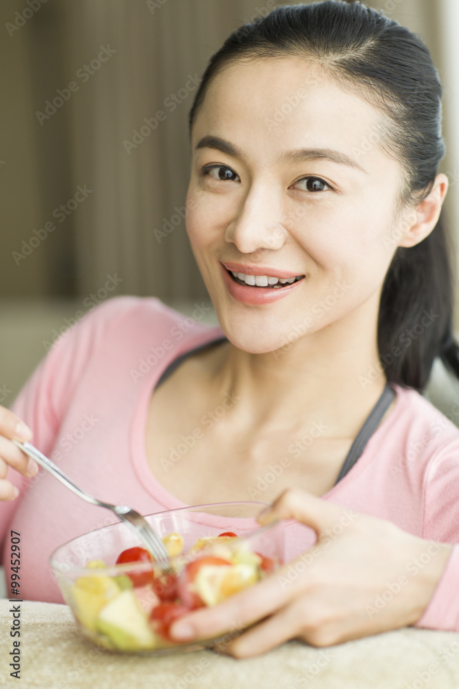 快乐的年轻女人吃水果沙拉