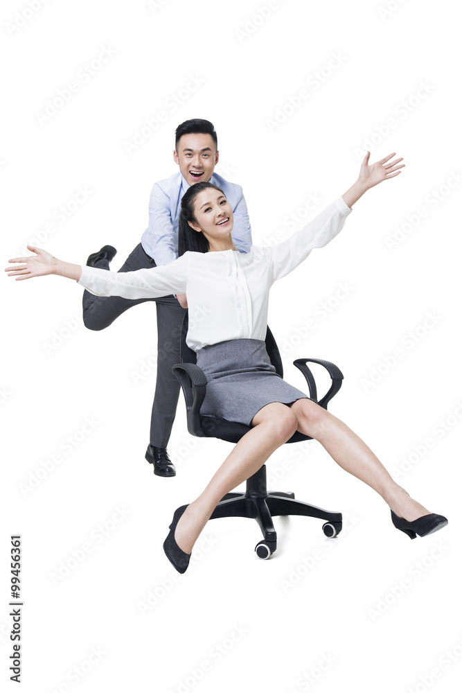 Businessman pushing businesswoman in rolling office chair